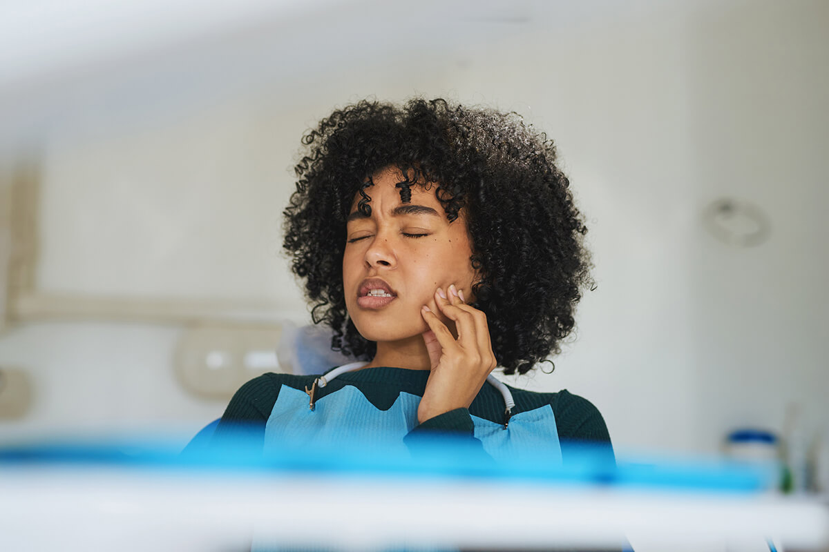 woman holds jaw in pain